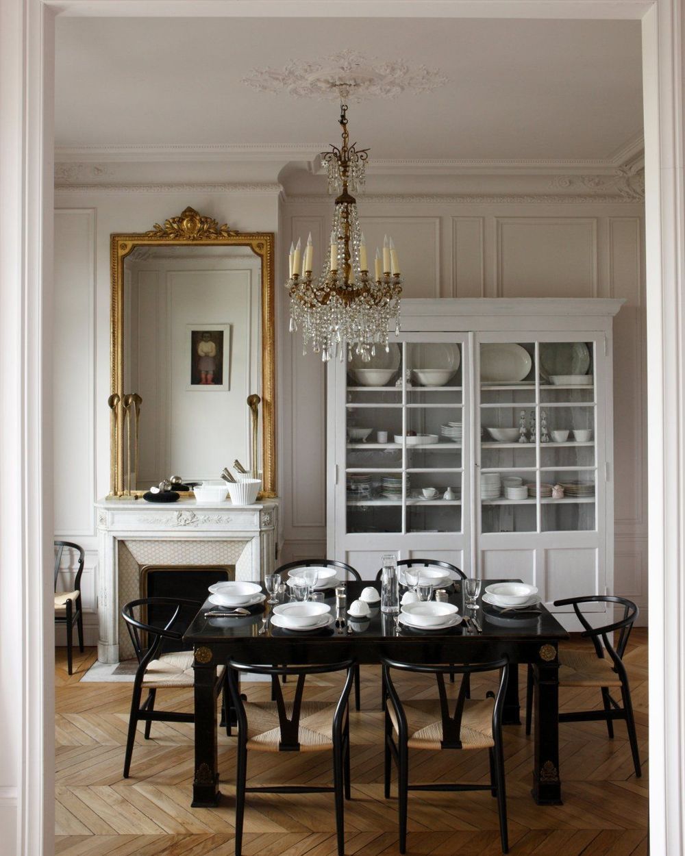 Parisian Dining Room design with Black dining table, Black wishbone chairs and crystal chandelier via Jean-Marc Palisse and CoteMaison